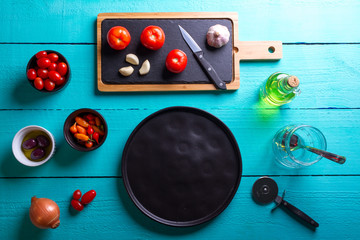 Pizza de Majericão sobre a mesa de madeira de cor turquesa com azeite, azeitonas pretas, orégano, molho de tomate