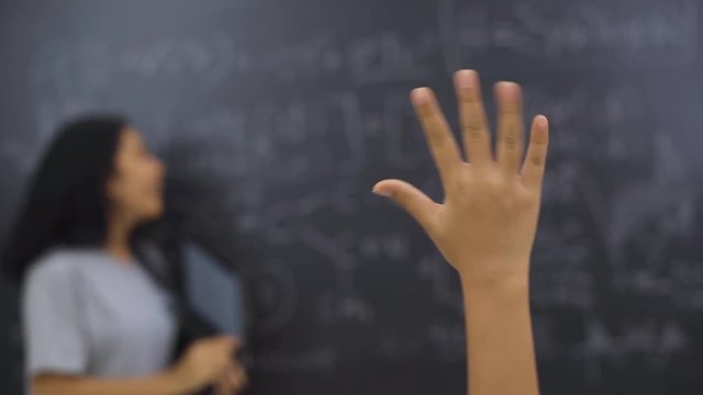 Female teacher answering the student who raising hand up and asking in the classroom at school. Shot in 4k resolution