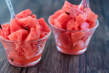 Dessert from sliced fresh watermelon in glass cups on a gray background.