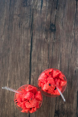 Dessert from sliced fresh watermelon in glass cups on a gray background.