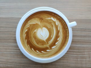 cup of coffee on wooden table ,latte art ,closeup