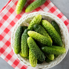 Whole fresh organic cucumbers in a white basket on a gray background. Soft focus. Top view.
