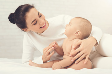 Mother playing with her baby in bedroom.