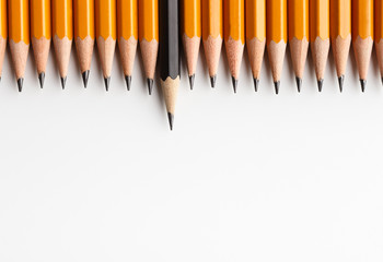 Row of classic yellow pencils with one black protruding