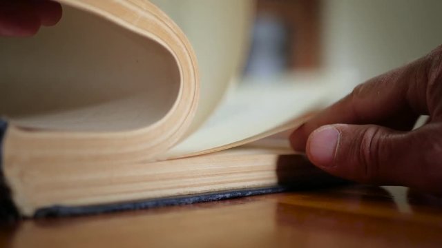 Caucasian man reading, turning old book pages, shallow depth of field.