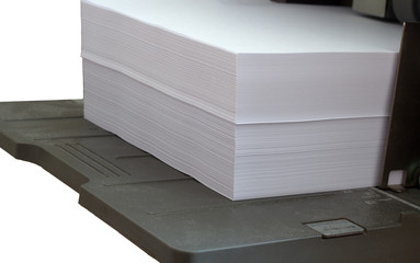 A stack of white paper lies on the printer's input tray ready for printing.