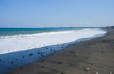 Ocean coast with black volcanic sand on the island of Bali, Indonesia.