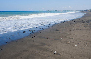 Ocean coast with black volcanic sand on the island of Bali, Indonesia.