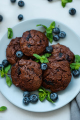 Chocolate cookies with chocolate chips and blueberry on gray wooden background. Summer food. Soft focus. Top view.