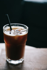 Iced coffee in a tall glass on wood at coffee shop