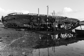 Old broken wooden ship on the shore. Black and white photo. Dramatic view.