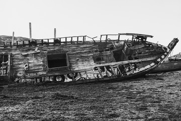 Old broken wooden ship on the shore. Black and white photo. Dramatic view.