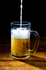 Caneca de cervaja sobre a mesa de madeira natural e fundo preto