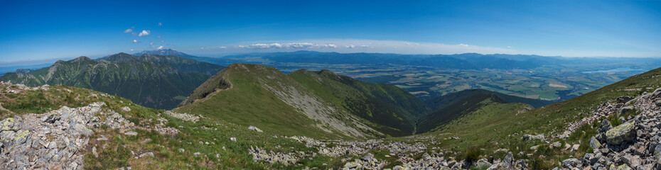 wide panoramic view with top of Baranec peak on Western Tatra mountains or Rohace panorama. Sharp green mountains with hiking trail on ridge. and Liptov valley. Summer blue sky background