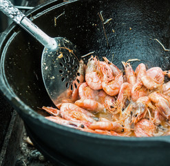shrimp are cooked in a large cauldron on fire.