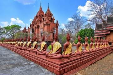 Buddha statue arranged on low wall surrounding temple church of Khao phra angkhan temple on extinct volcanoes at Buriram province Thailand, Scenery of religious sculpture in blue sky and white cloud.