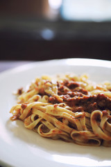 spaghetti Bolognese with minced beef and tomato sauce garnished with parmesan cheese and basil , Italian food