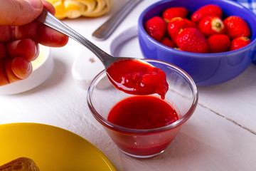 Café da manhã com ovos fritos, pão e manteiga, morangos, leite, cereais, torrada com geléia de morango e suco de laranja sobre a mesa de madeira branca