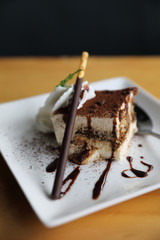 tiramisu cake dessert with cream mint and chocolate sauce on wood background