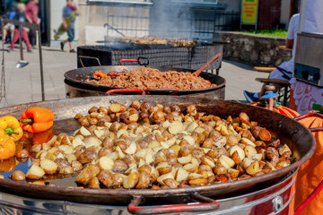 Fried potatoes cooked in big metal wok. street market