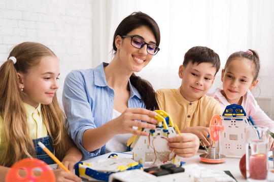 Children constructing robots with teacher in class