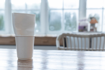 closeup of white takeaway paper cup with tissue napkin on wooden table.