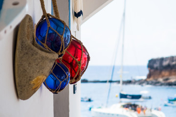 Exterior wall decoration in the form of a decorative felt shoe and three glass balls. In the background a holiday backdrop, which gives an idea of the sea, boats and a cliff