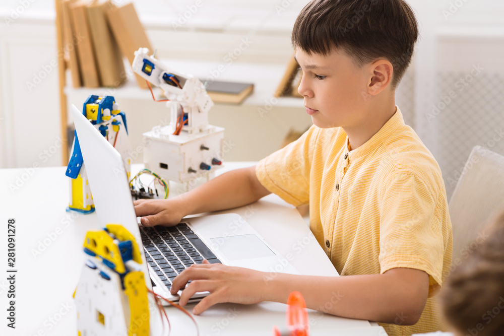 Poster schoolboy creating robotics project, typing plan in laptop