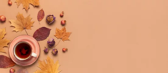 Poster Autumn Flat lay composition. Cup of tea, autumn dry bright leaves, roses flowers, orange circle, cones, decorative pomegranate, cinnamon sticks on brown beige background top view. Autumn, fall concept © olgaarkhipenko