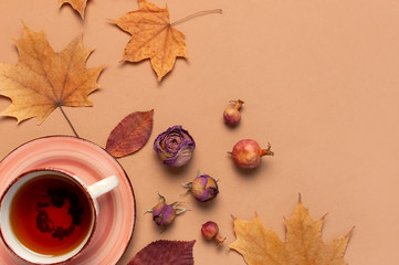 Autumn Flat lay composition. Cup of tea, autumn dry bright leaves, roses flowers, orange circle,...