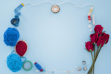 Blue wool; measuring tape; thread spool; button ; thimble and roses on blue background