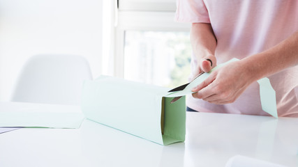 Woman's hand cutting the paper wrapped on box with scissor