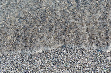 Closeup of sandy beach with soft incoming waves. Selective focus