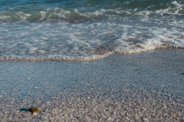 Closeup of sandy beach with soft incoming waves. Selective focus