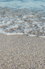 Closeup of sandy beach with soft incoming waves. Selective focus