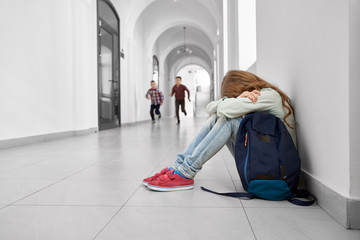 One school girl sitting on floor when her friends running.