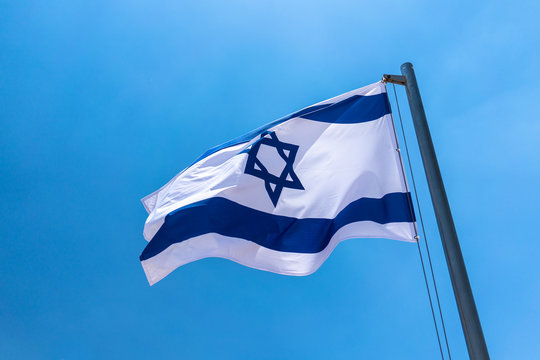 Israeli flag blowing in the wind in a Hebrew cemetery in Jerusalem, Israel.
