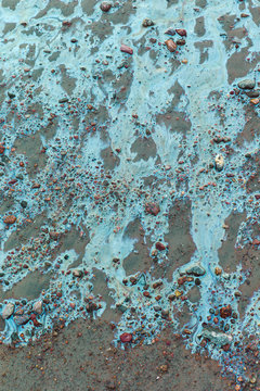 Colored water on stones and sand.Environmental pollution