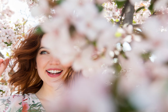 Woman smiling in behind cherry blossom tree