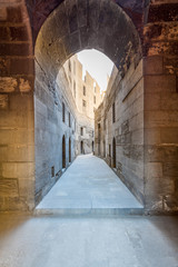 Obraz premium Narrow passage with old grunge stone walls leading to Sultan Hasan Mosque, Cairo, Egypt