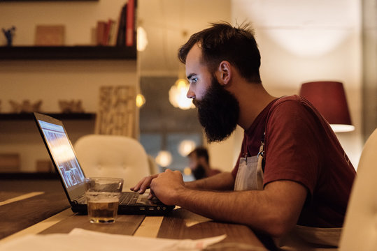 Man scrolling laptop and having drink