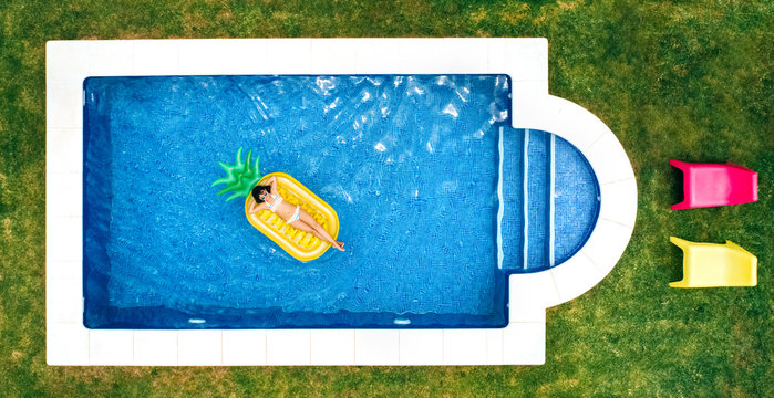 Little girl lying on a pineapple-shaped float in a swimming pool