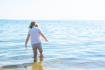 cute little girl stands in the lake sea in the summer