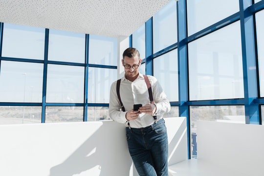 Businessman using cell phone at the window in modern office