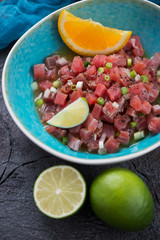 Turquoise plate with tuna fillet ceviche marinated in lime and orange juice, vertical shot