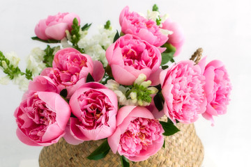 Bouquet of beautiful pink peonies in straw basket