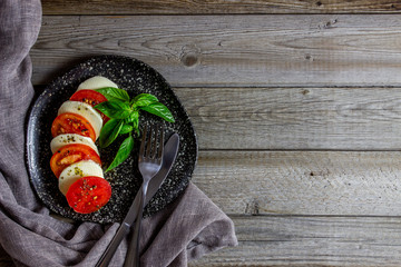 Italian caprese salad with mozzarella and tomatoes. Wooden background. Healthy food.