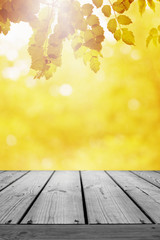 Naklejka na ściany i meble Wooden table and blurred leaf nature autumn background.