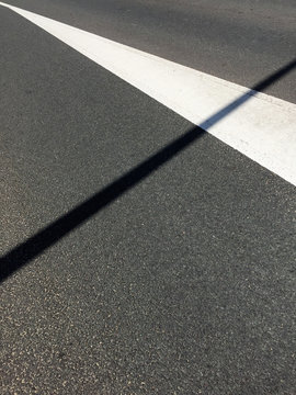 asphalt road with white line and shadow of a pole