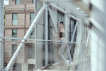Raven haired young lady with tattoos posing on the bridge